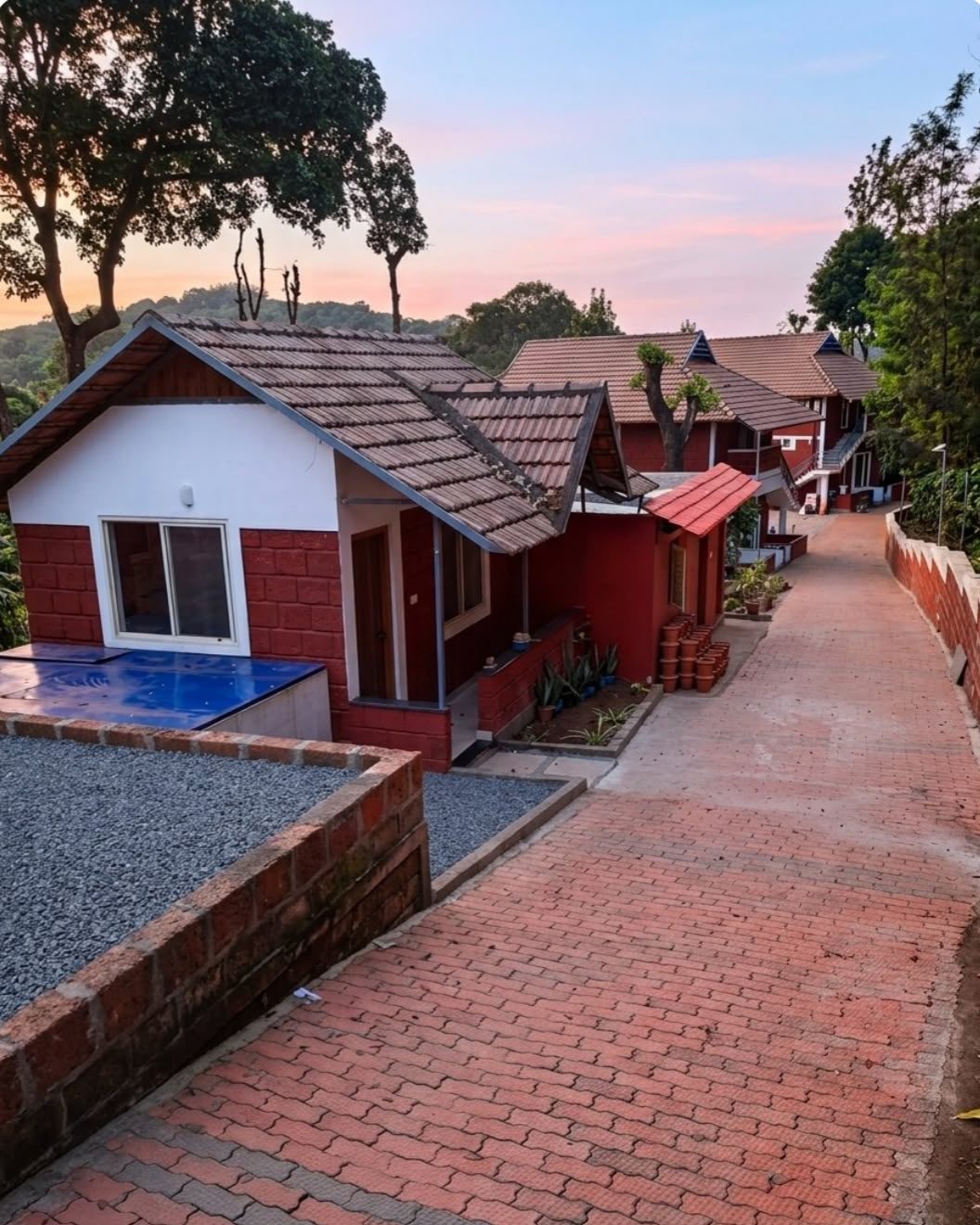 Red-brick cottages with tiled roofs along a brick path, at dusk